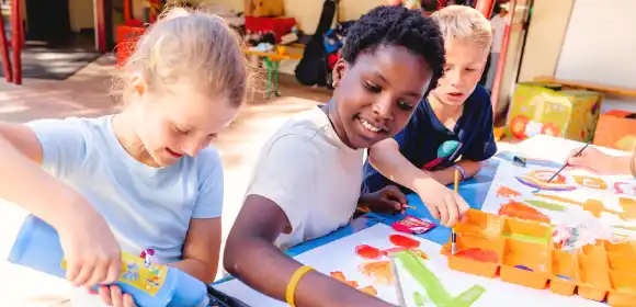 Kinder basteln gemeinsam an einem Tisch.