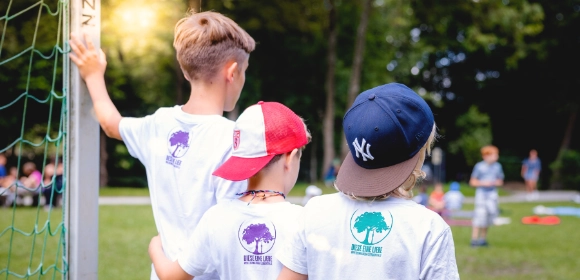 Kinder beobachten gemeinsam ein Spiel auf dem Sportplatz.