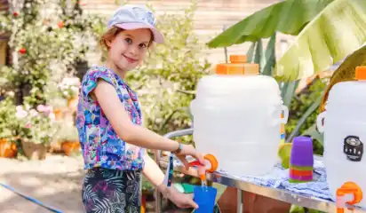Kind füllt an einem Getränkestand einen Becher.