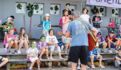 Kindergruppe sitzt vor einer Bühne bei einem Programm im Ferienwaldheim.