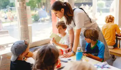 Betreuerin begleitet Kinder beim Essen im Speisesaal.
