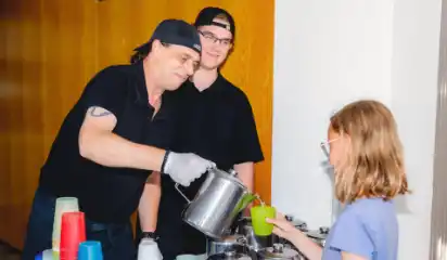 Küchenhelfer geben einem Kind Essen aus.